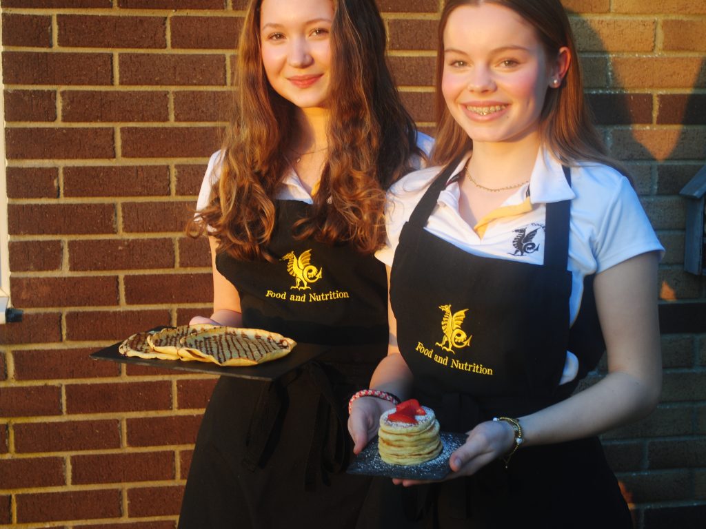 Two Queen's College students holding pancakes