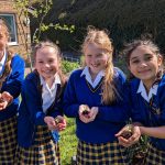 Queen's College students happily showing the seedlings they are about to plant in the ground