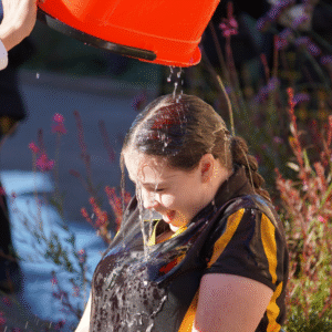 A bucket of water being poured over a girl's head 