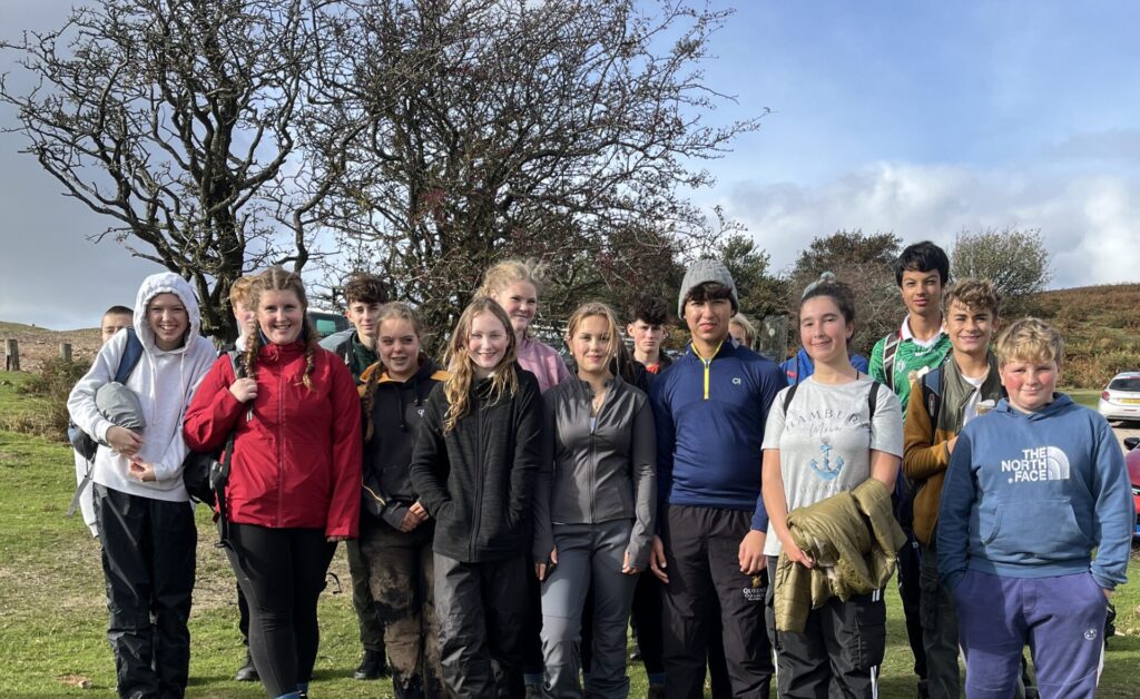 A group of pupils standing outside next to a tree.