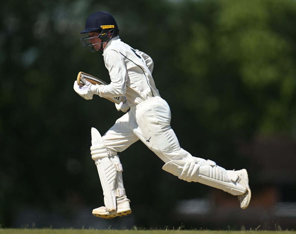 Pupil jumping in the air playing cricket.