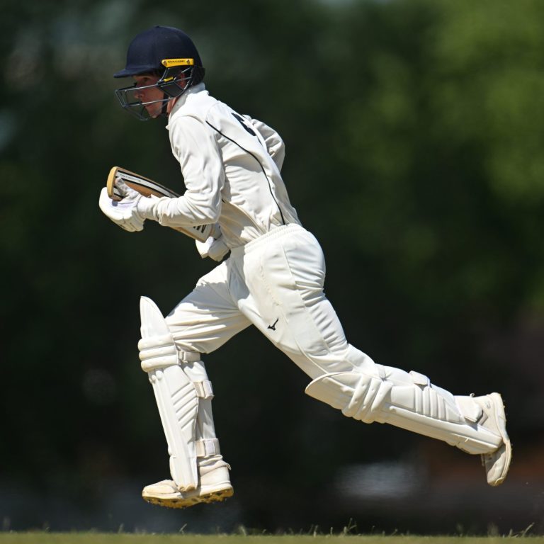 Pupil jumping in the air playing cricket.