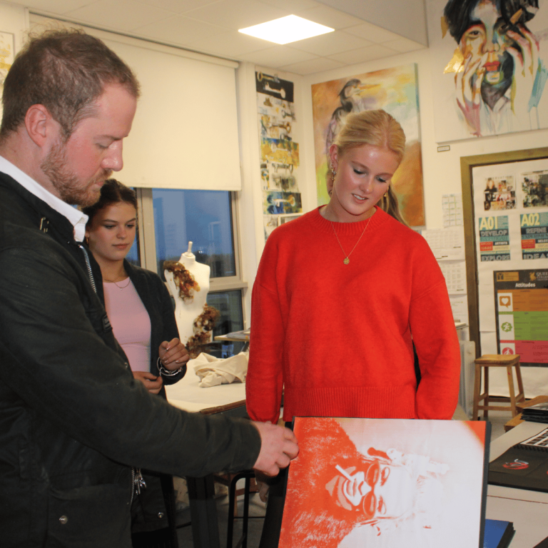 Ollie and a pupil looking at a sketch book together.