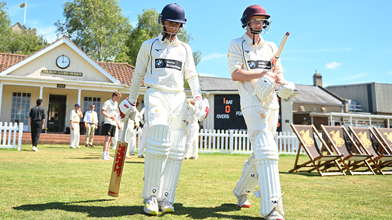 Queen's College batters walk out for cricket match